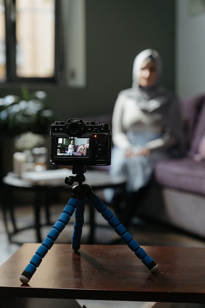 services-03 Camera on a tripod filming a woman in a cozy living room setting for a vlog.